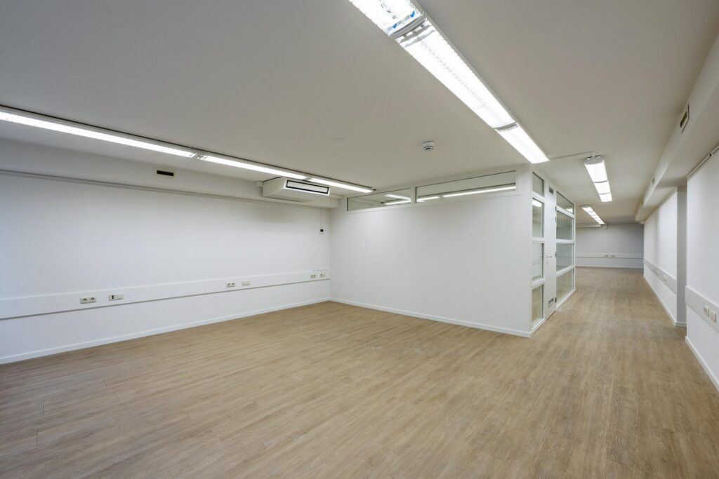 Leeg kantoorruimte met houten vloer en glazen tussenwanden aan de Prins Hendrikkade.